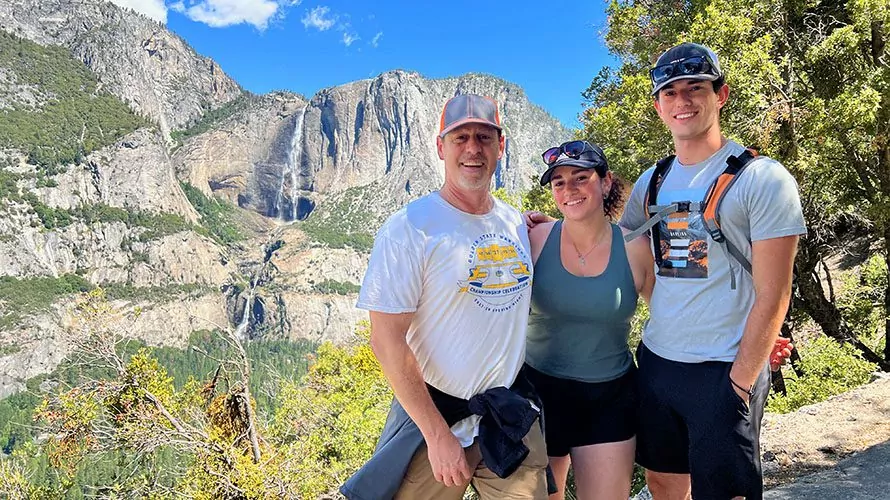 3 hikers on the Fourmile Trail in Yosemite, Yosemite Falls behind