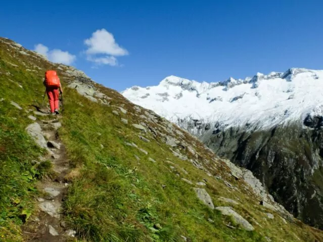 Hiker on steep trail with glaciers.