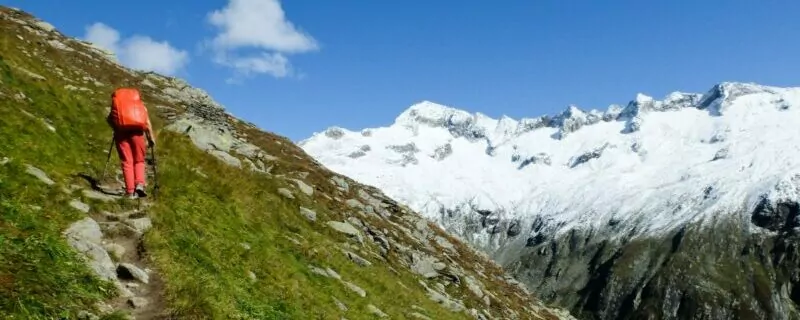 Hiker on steep trail with glaciers.