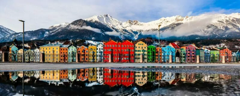 Water reflection of the colourful cityscape of Innsbruck at the Mariahilf district with the snowy Nordkette mountain chain.