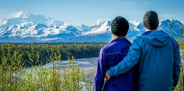 Young couple holding each other and standing in front of mount Denali formerly mount Mckinley, Alaska