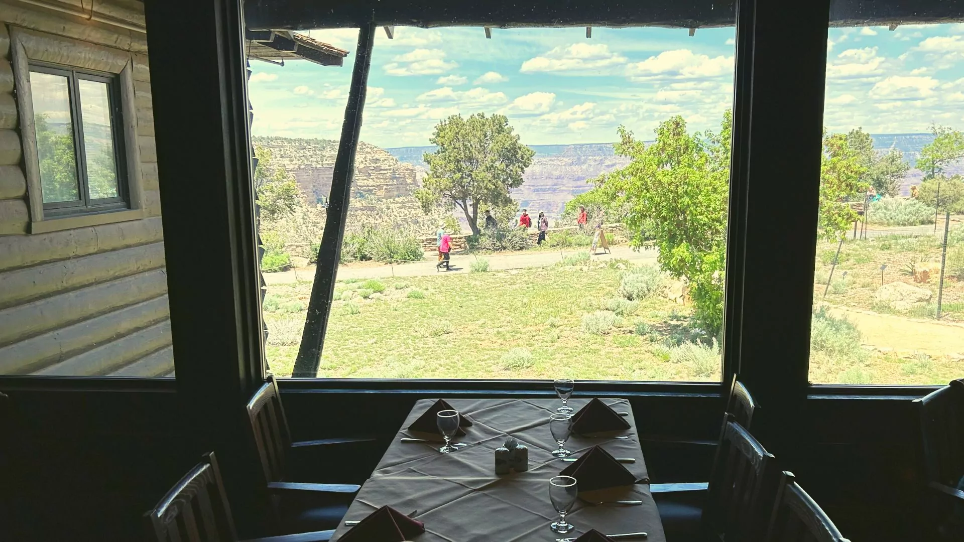 A set dinner table next to a large window looks out on the edge of the Grand Canyon