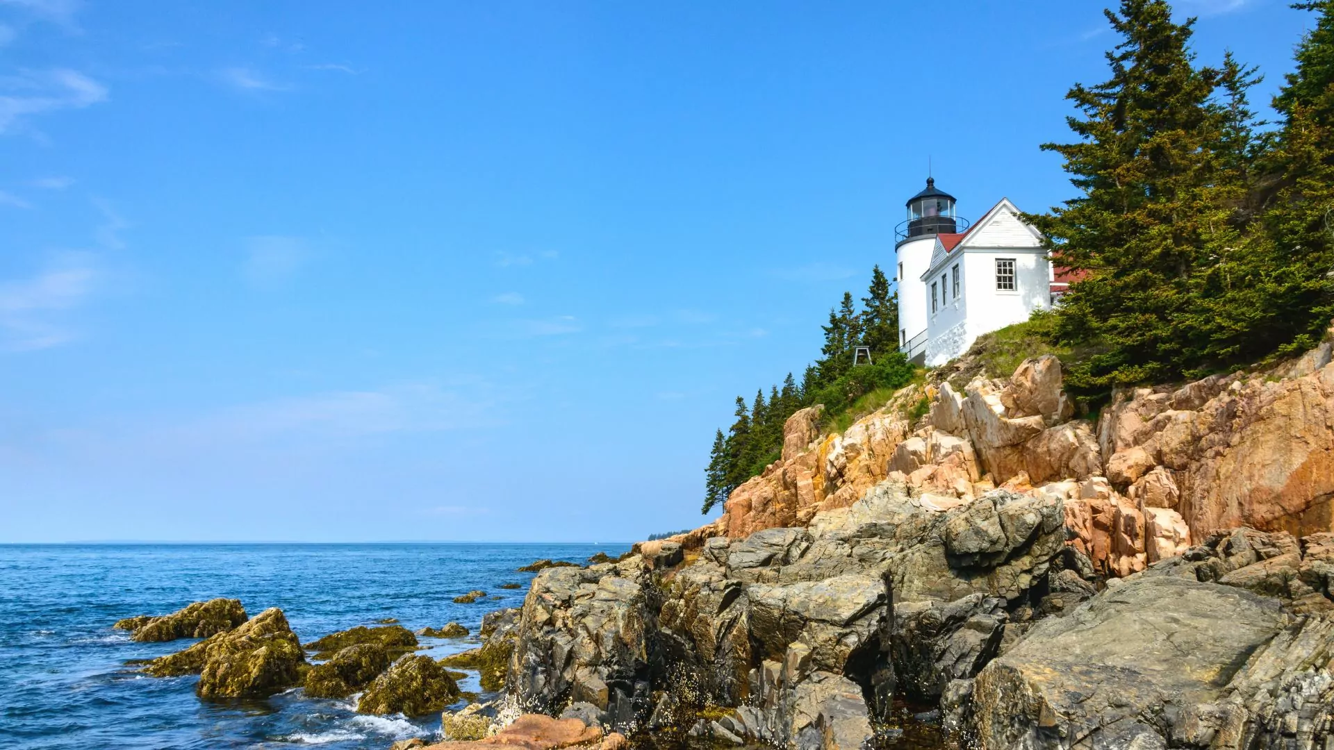 A lighthouse sits on the rocky Maine coast