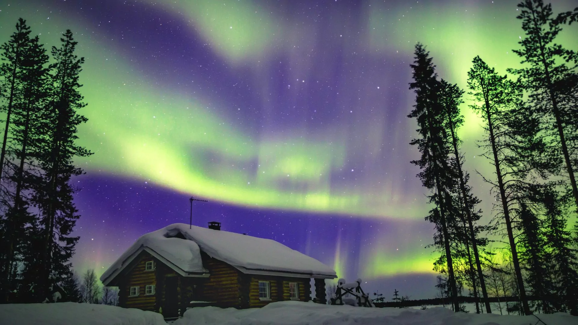 Northern lights display over snowy farm scene in Finland