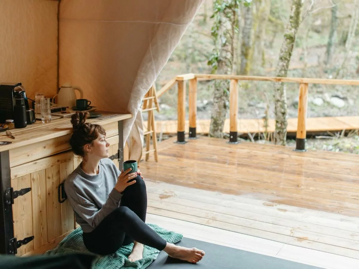 A woman sits inside a rustic yurt looking outside