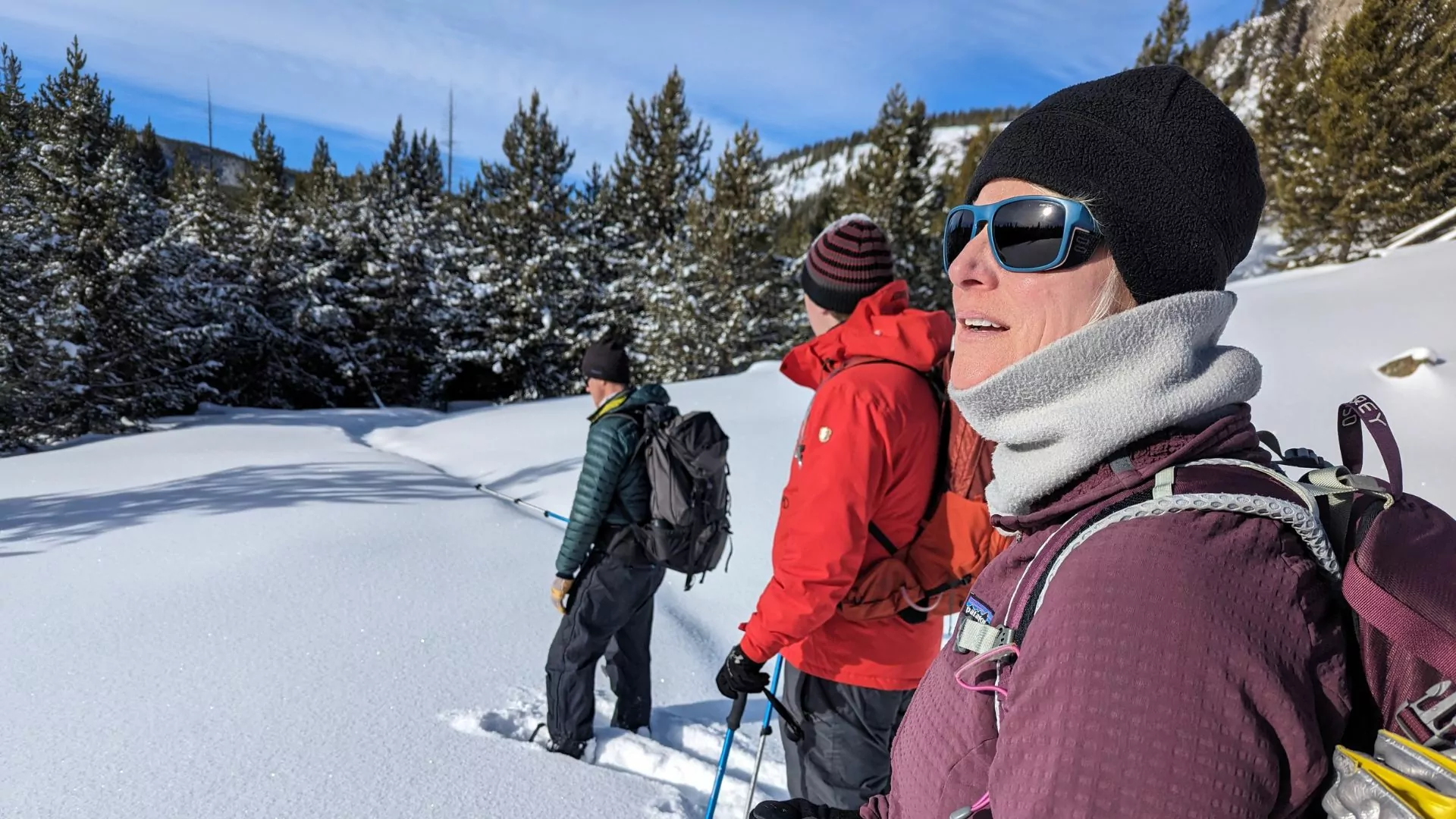 Hiker in warm layers looks out into a sunny winter afternoon