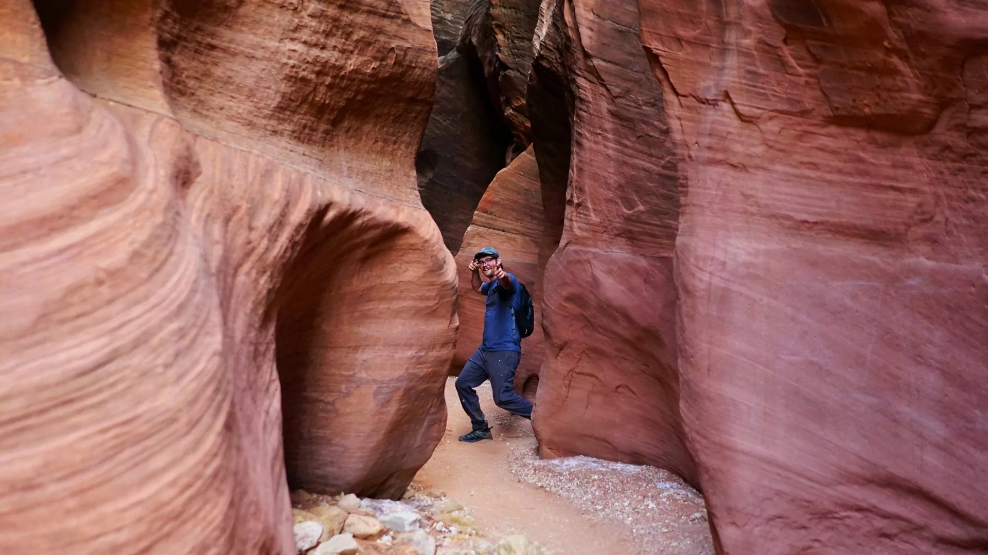 The author poses in a narrow slot canyon pointing at the camera
