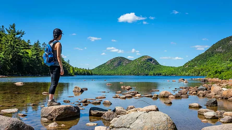 A female hiker exploring Jordan Pond in Acadia National Park, Maine.