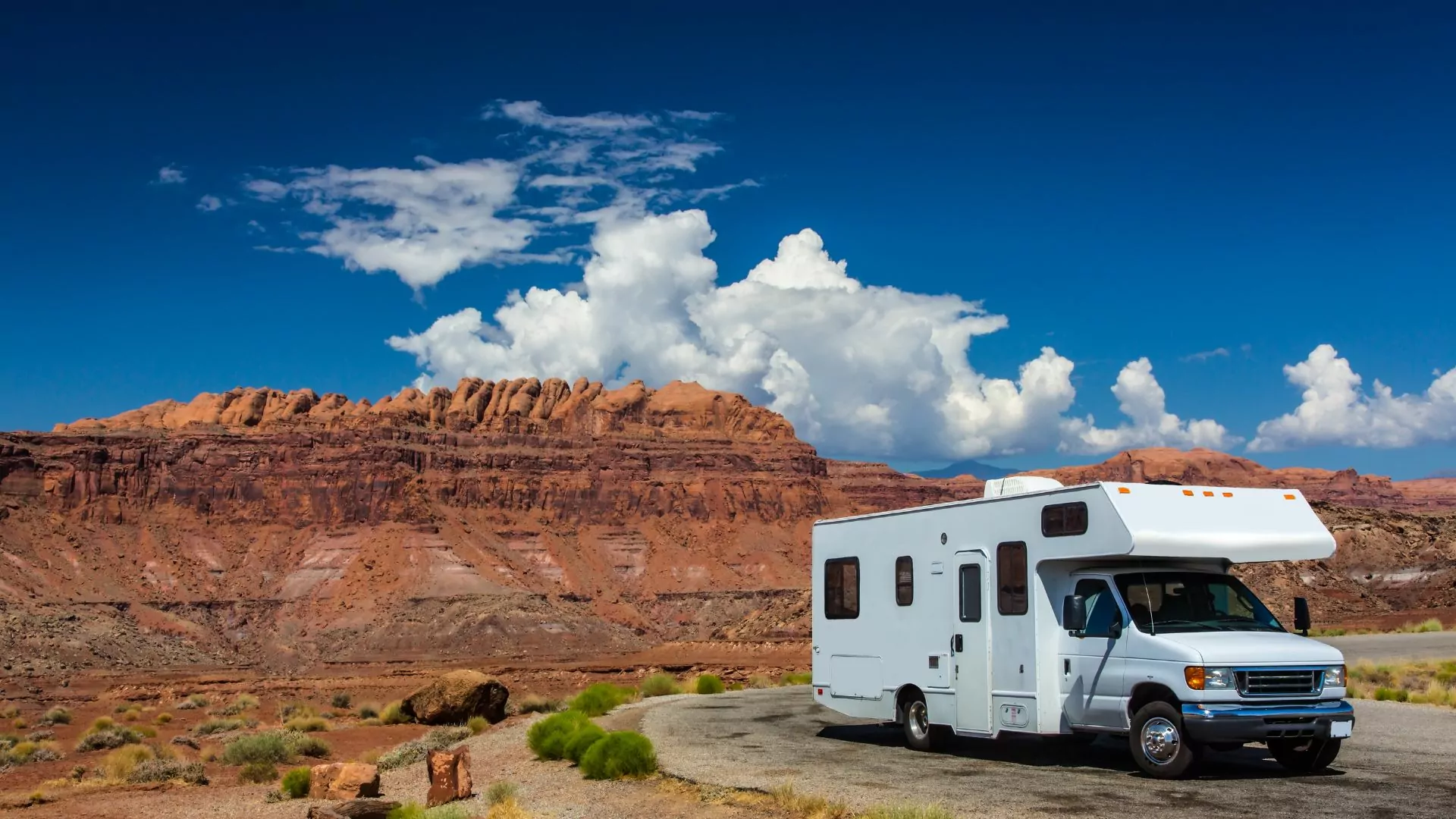 An RV sits parked in front of a red rock butte near Moab Utah