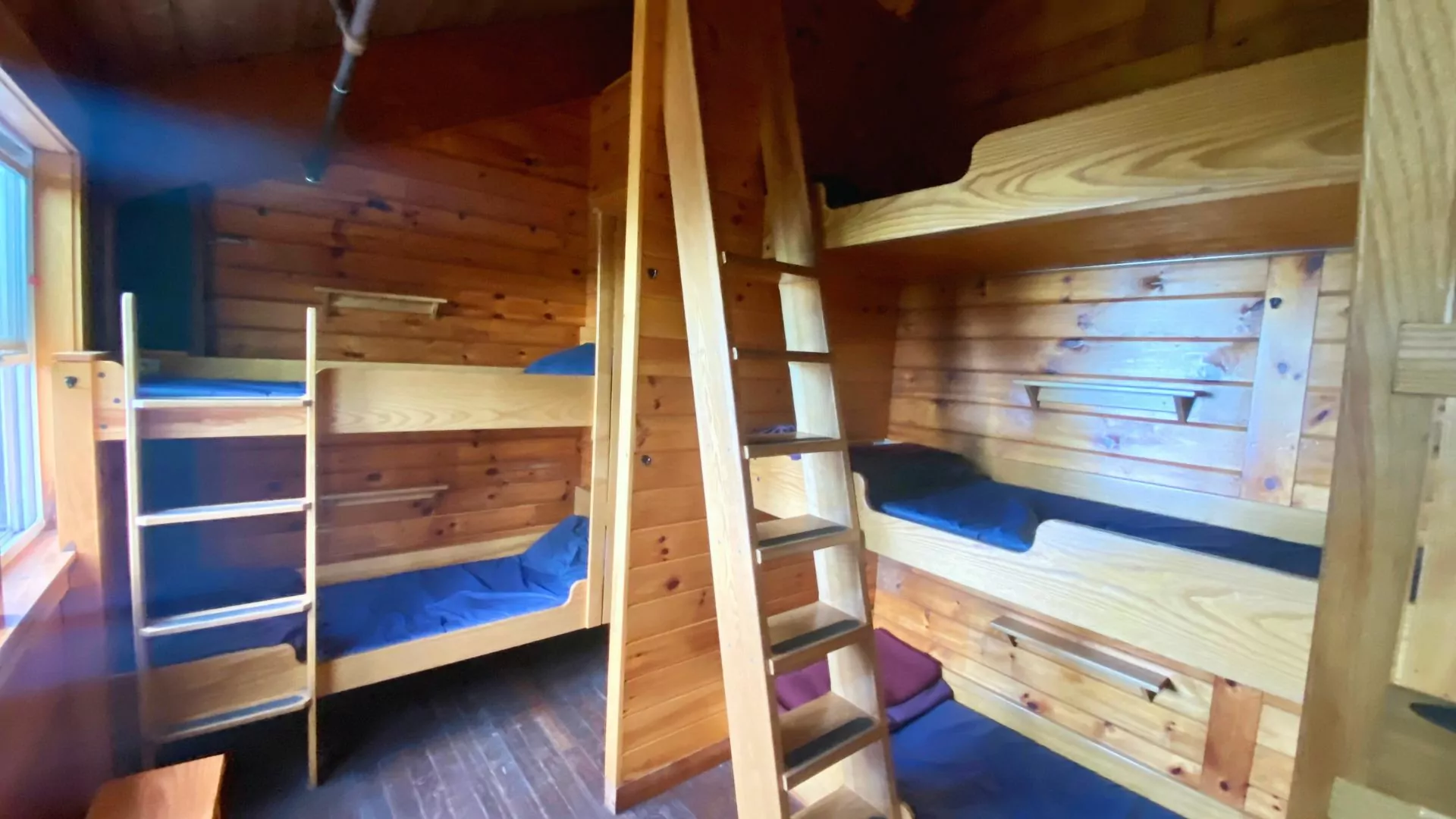 Rustic AMC hut bunk room with wooden bunk beds, ladder and matresses