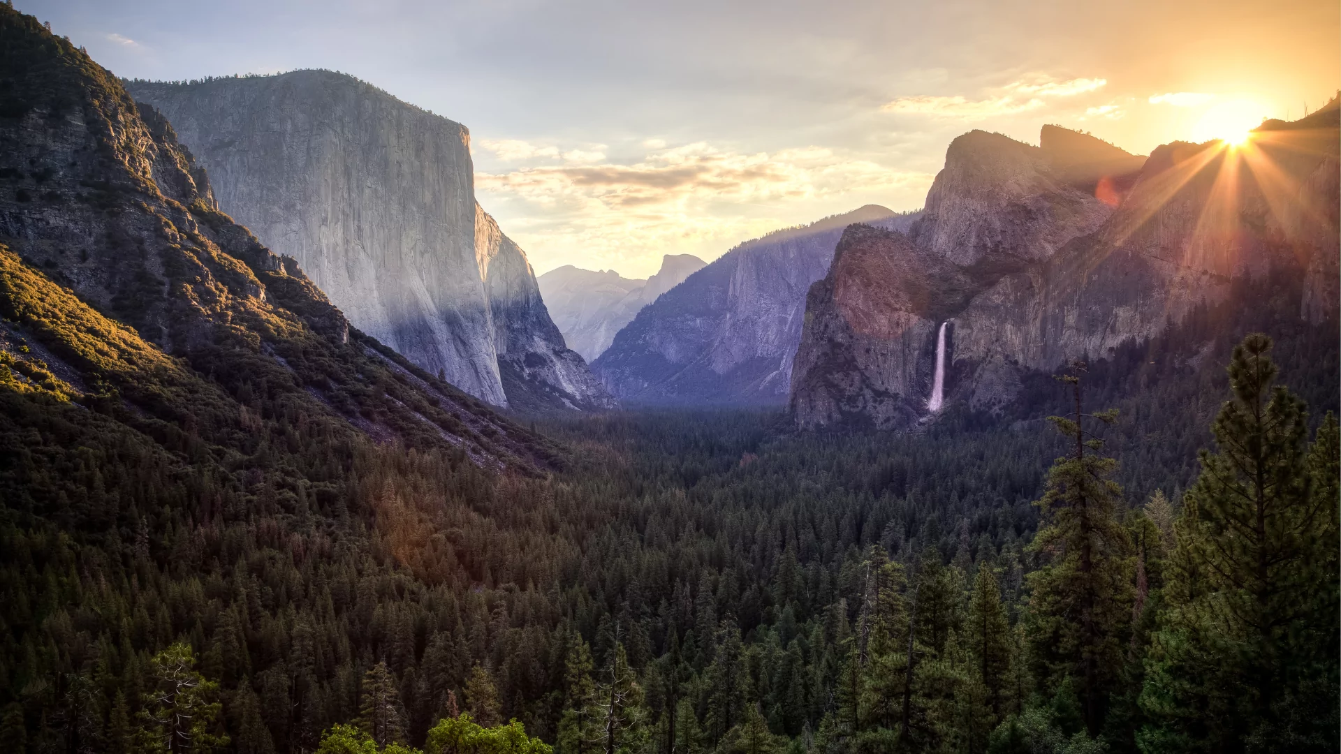 Light spills into Yosemite valley as the sun rise starts to crest above high granite walls