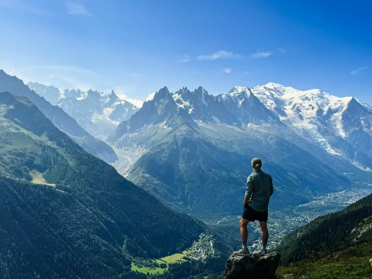 A hiker stands looking out at the Alps