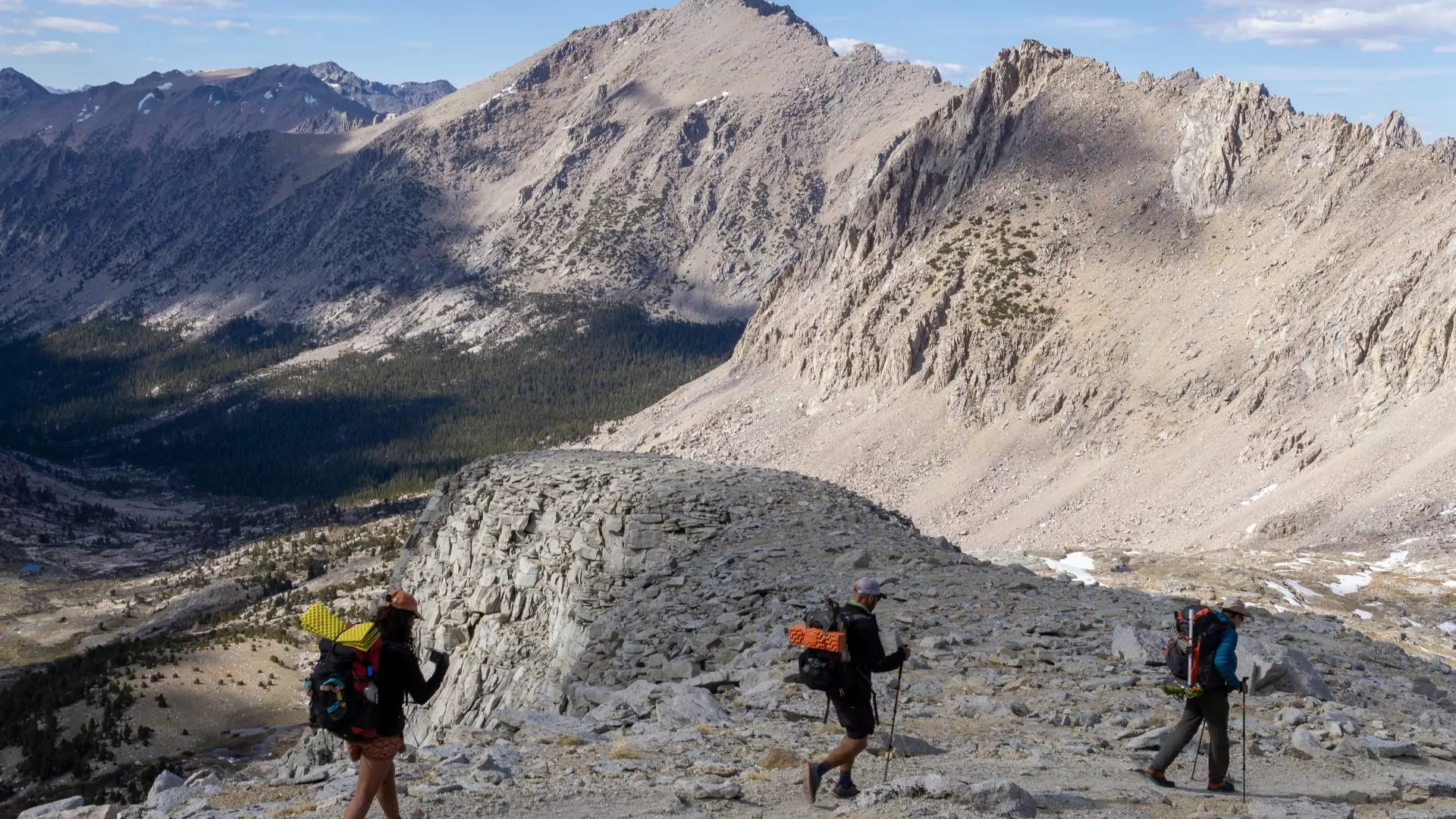 Three backpackers follow the John Muir Trail through the rugged peaks of the Sierra Nevada Mountains