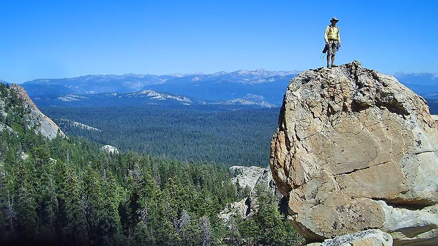 Rock climbers standing on top of cliff with view of the Sierras