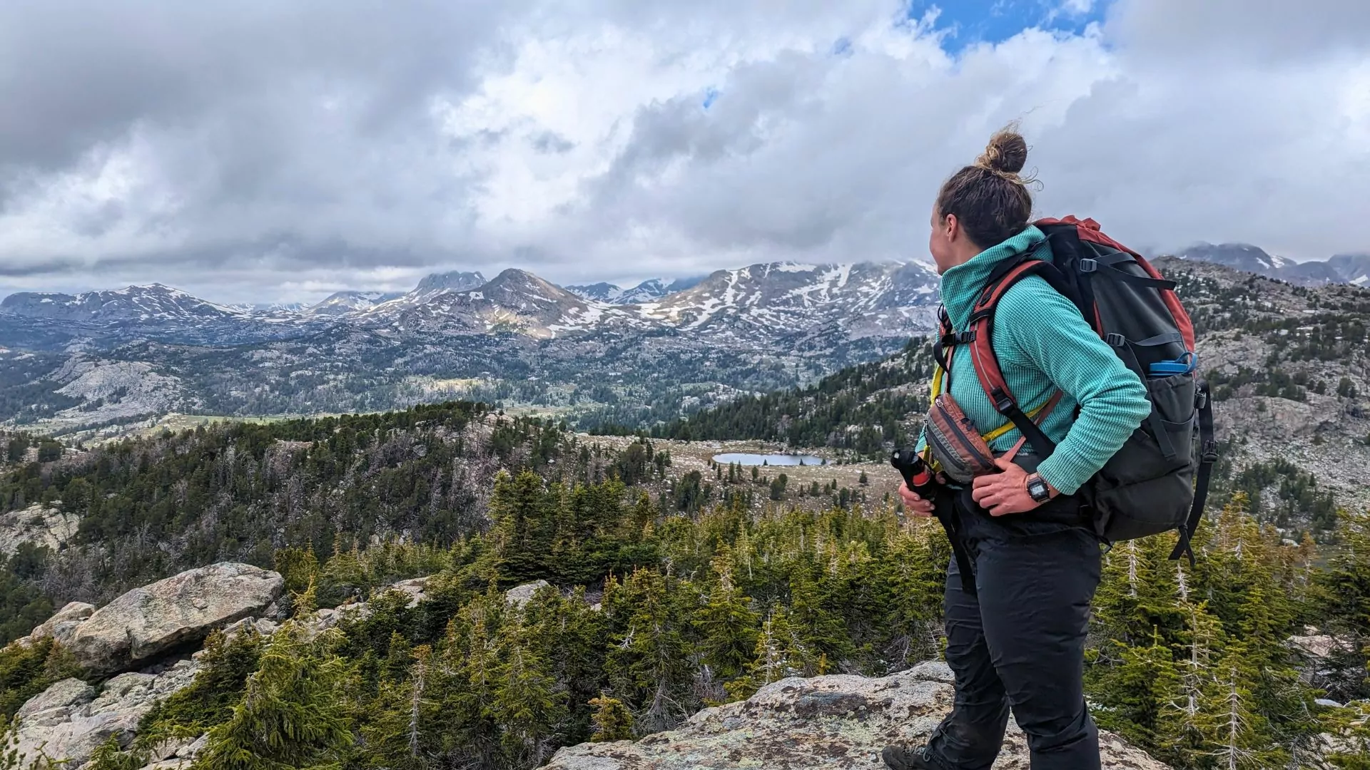 A woman wearing a backpack looks out in the distance