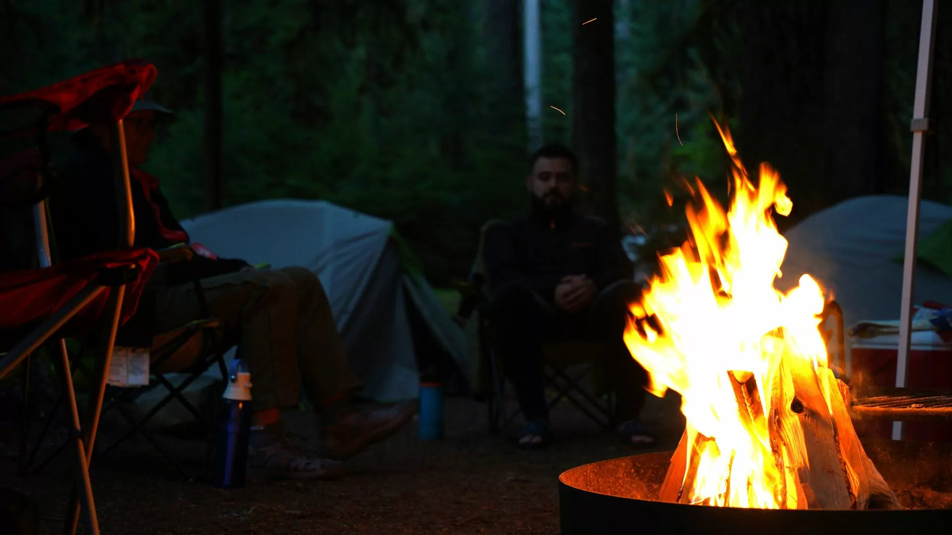 A campfire blazes in the darkness