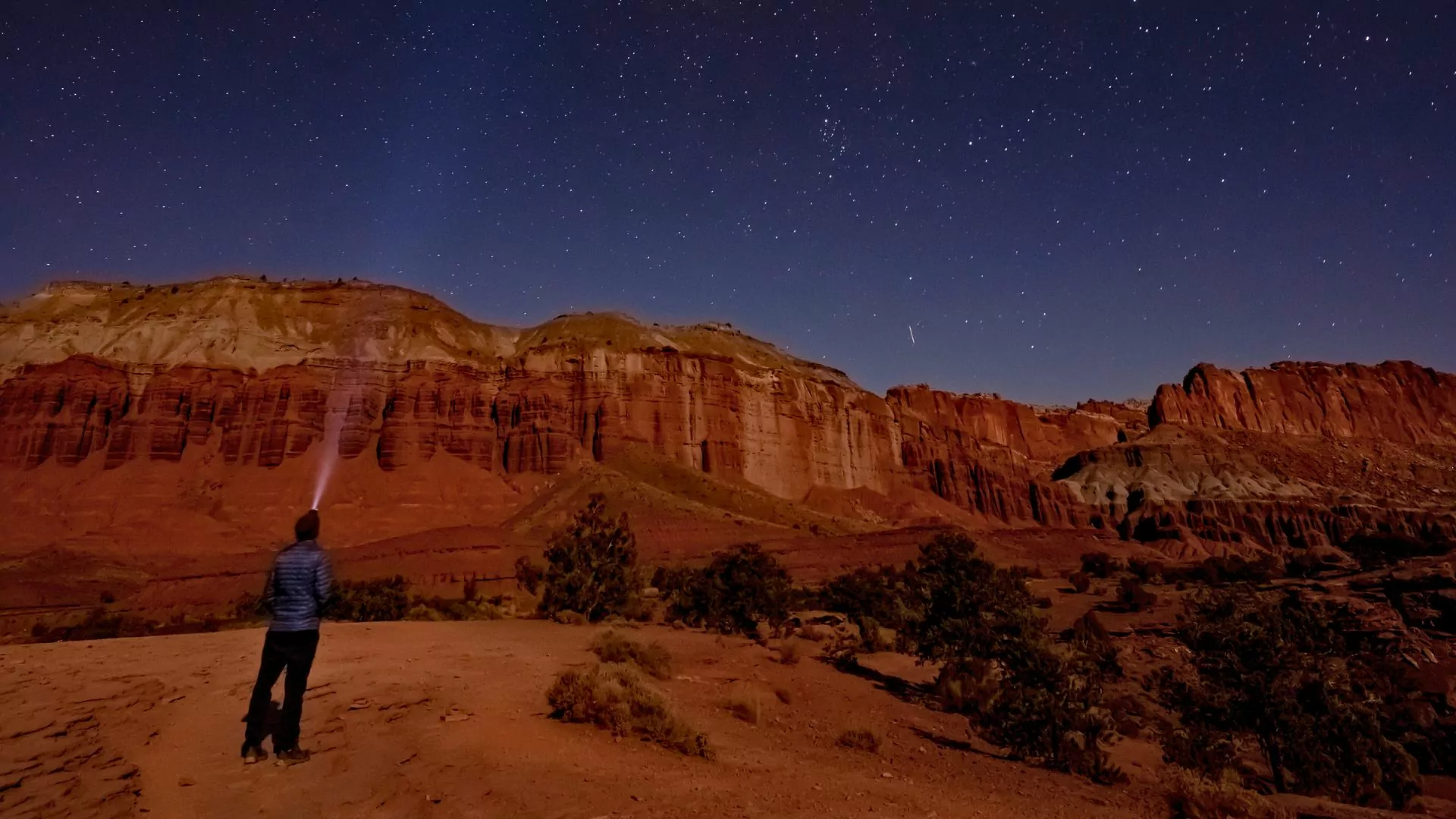 A person shines a flashlight at the night sky while stargazing in capitol reef national park