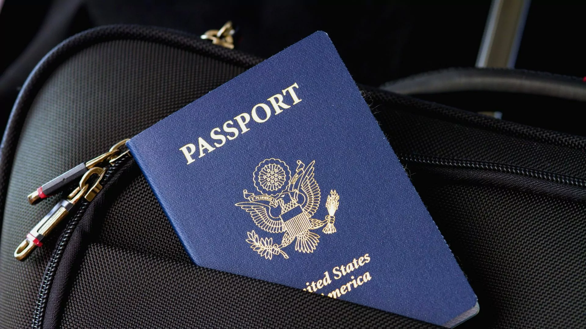 A US passport peeks out of a suitcase pocket