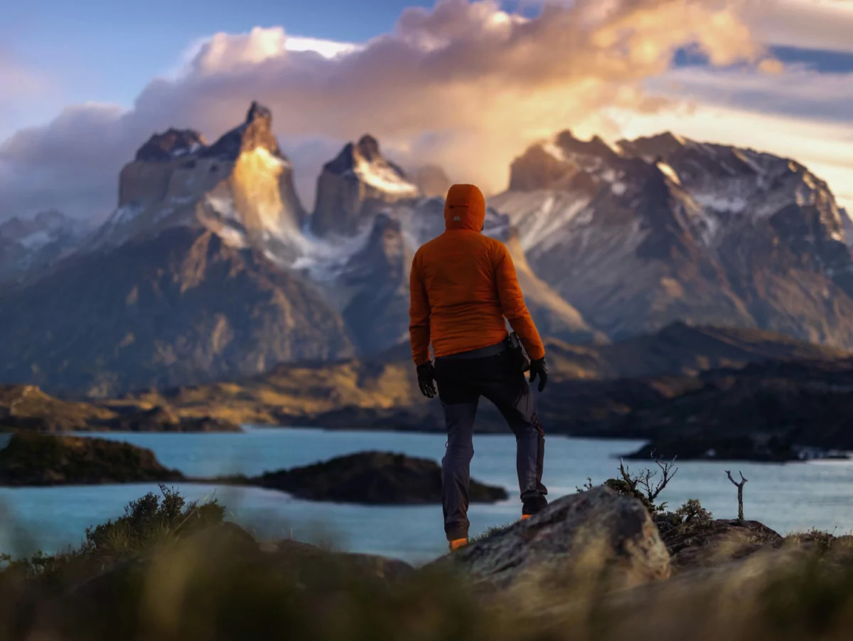 A solo hiker stands alone in front of a rugged mountain range