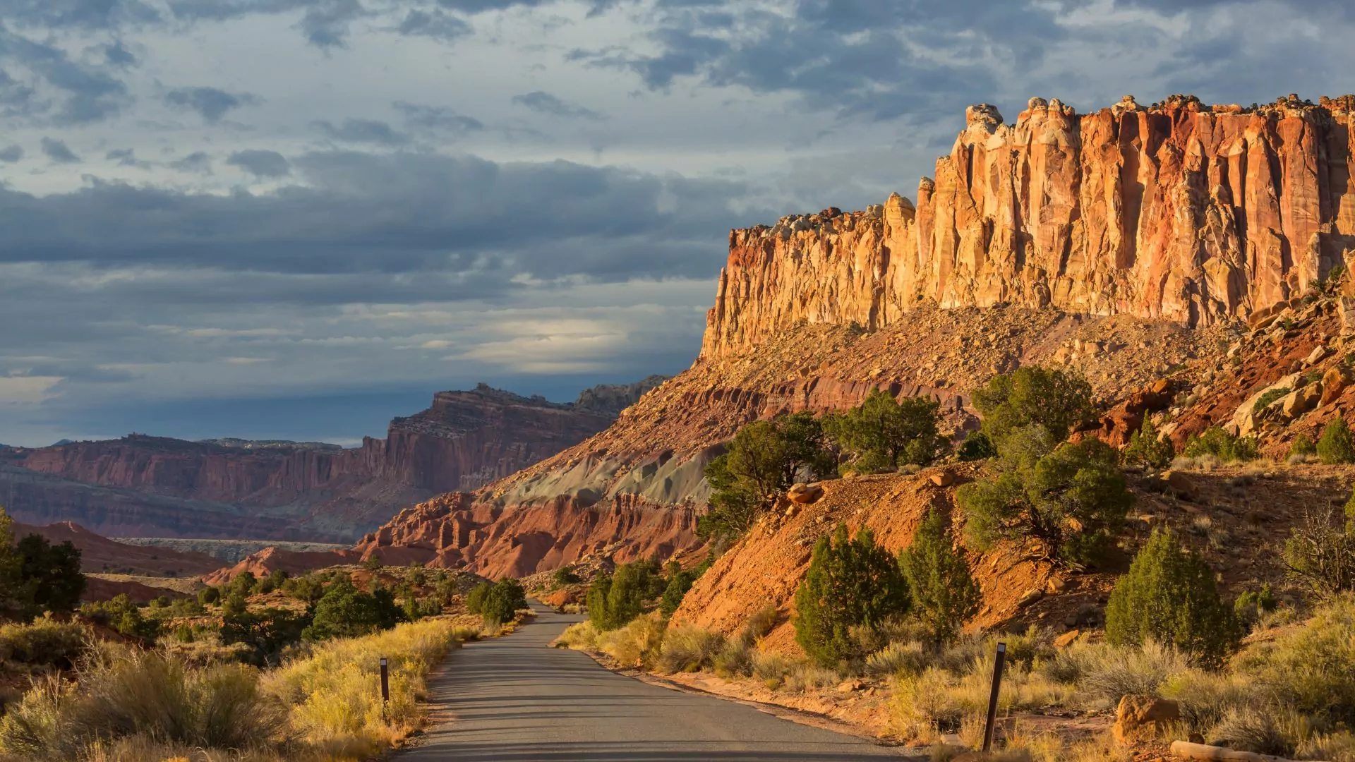 A paved road winds through capitol reef national park in golden hour