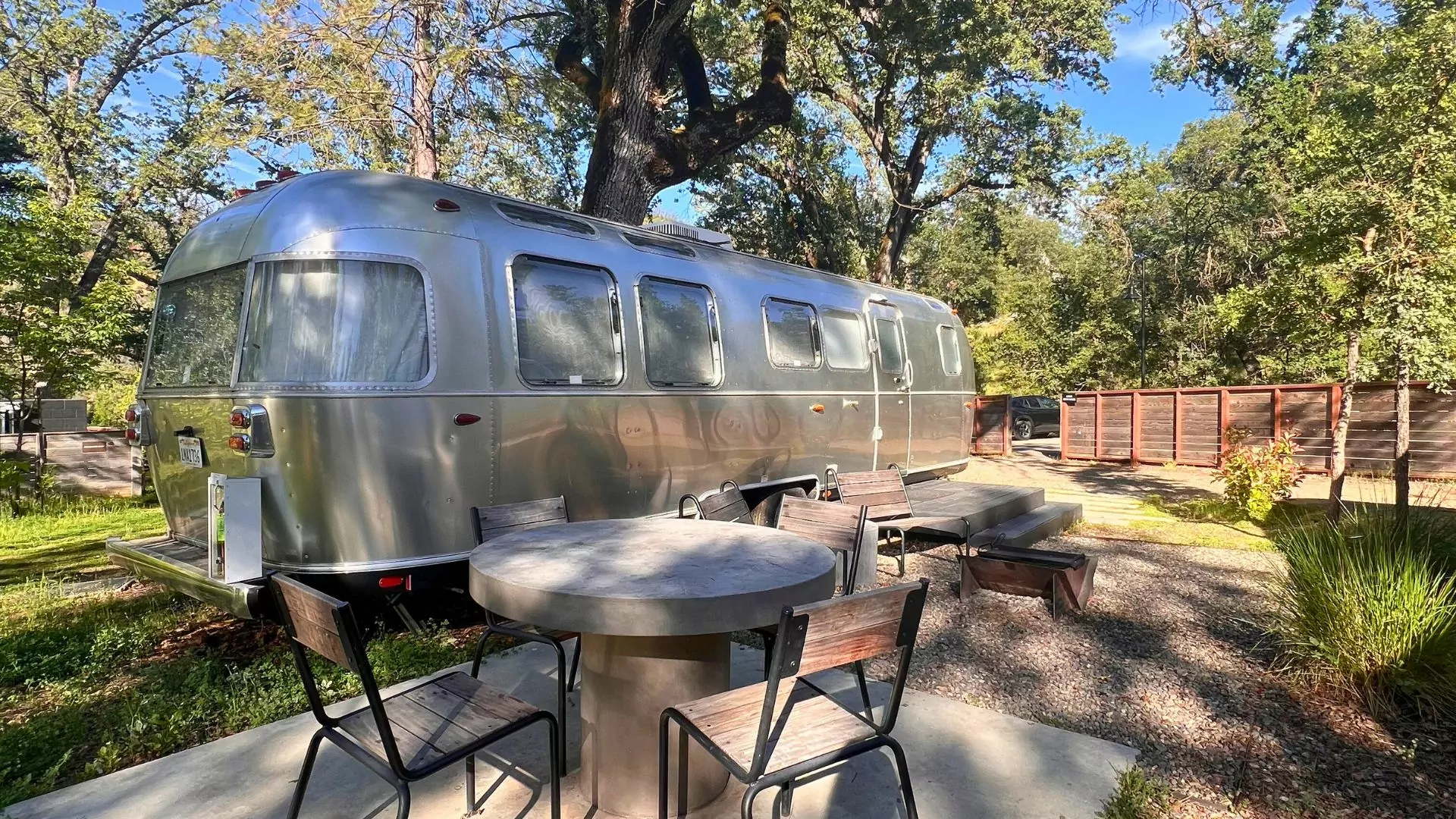 A table and chairs sit outside and airstream trailer
