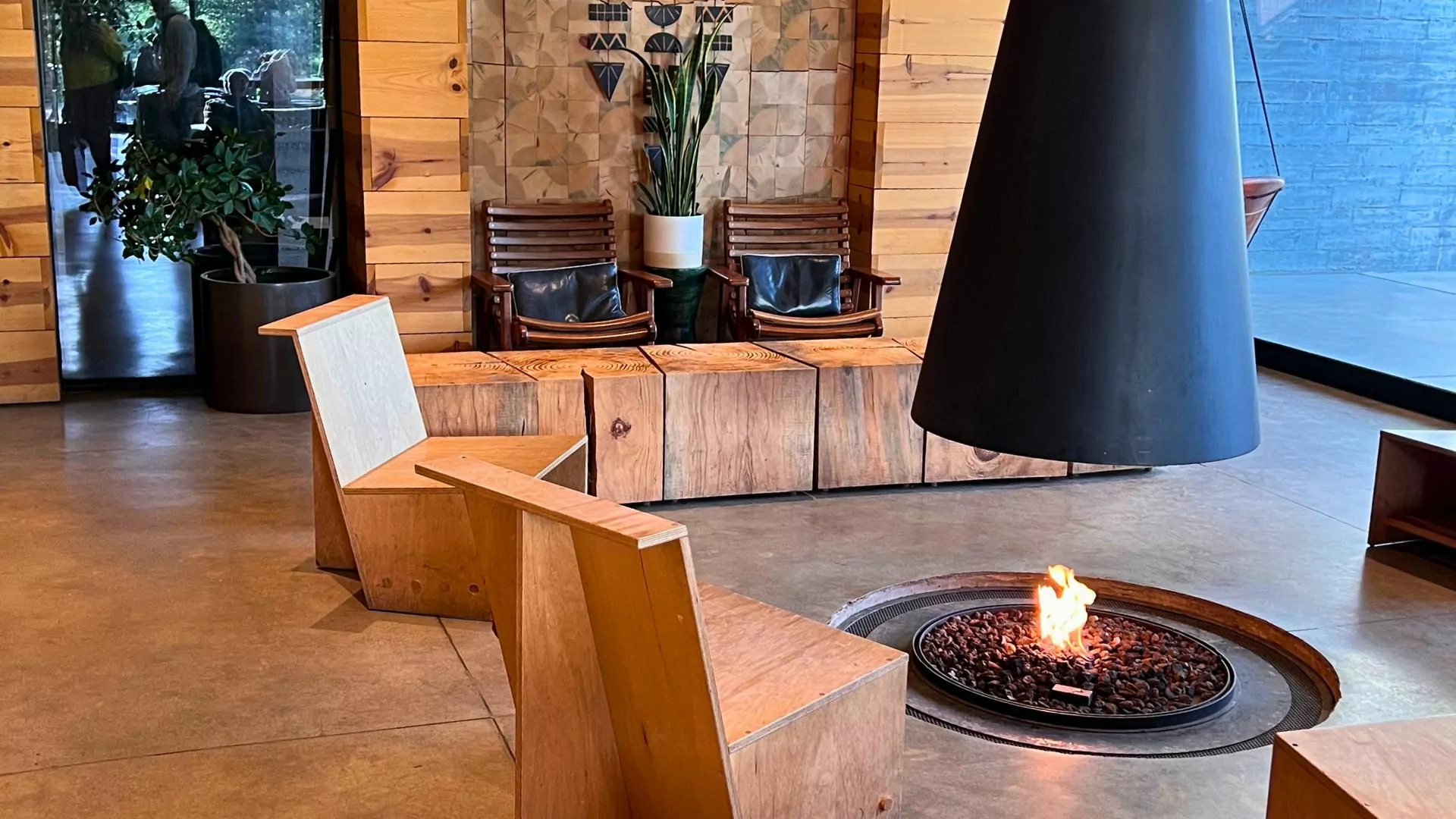 An indoor firebit and chairs sit in a wood paneled lobby