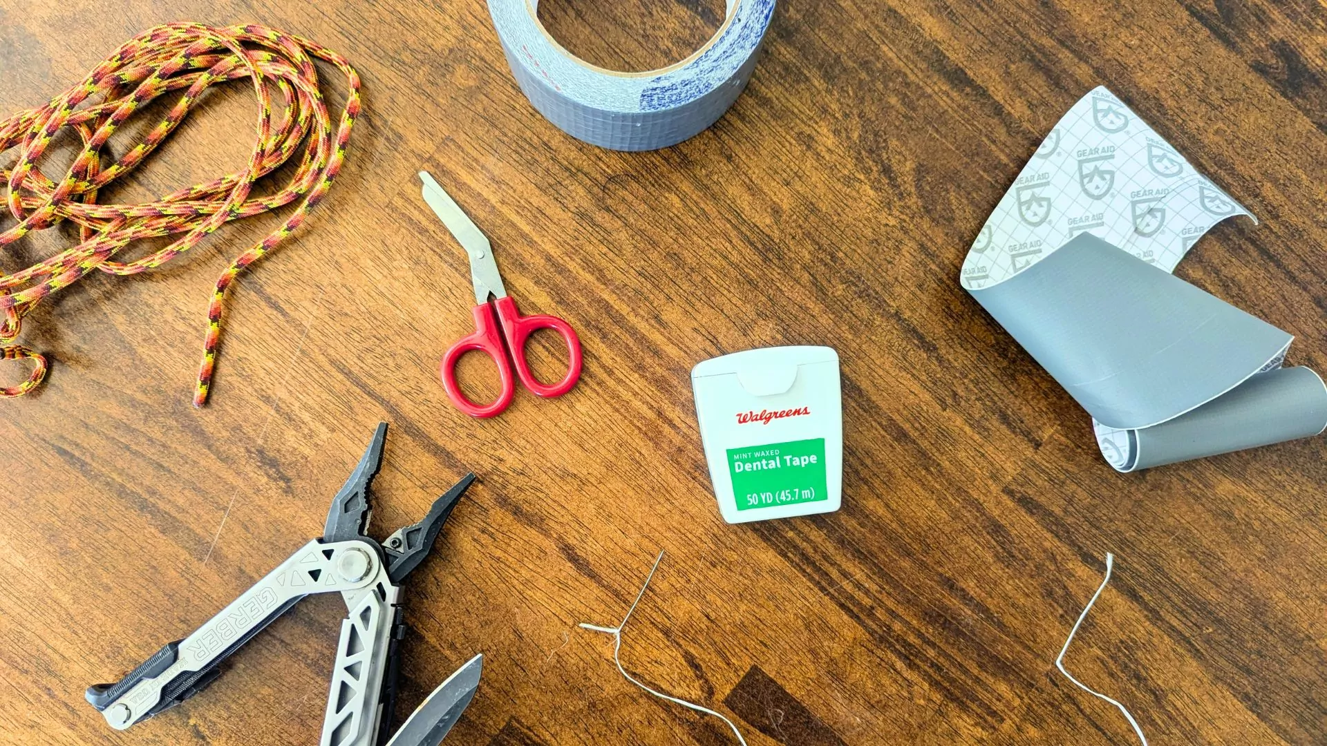 Repair supplies like parachute cord, duct tape, scissors, and a needle lie spread out on a table