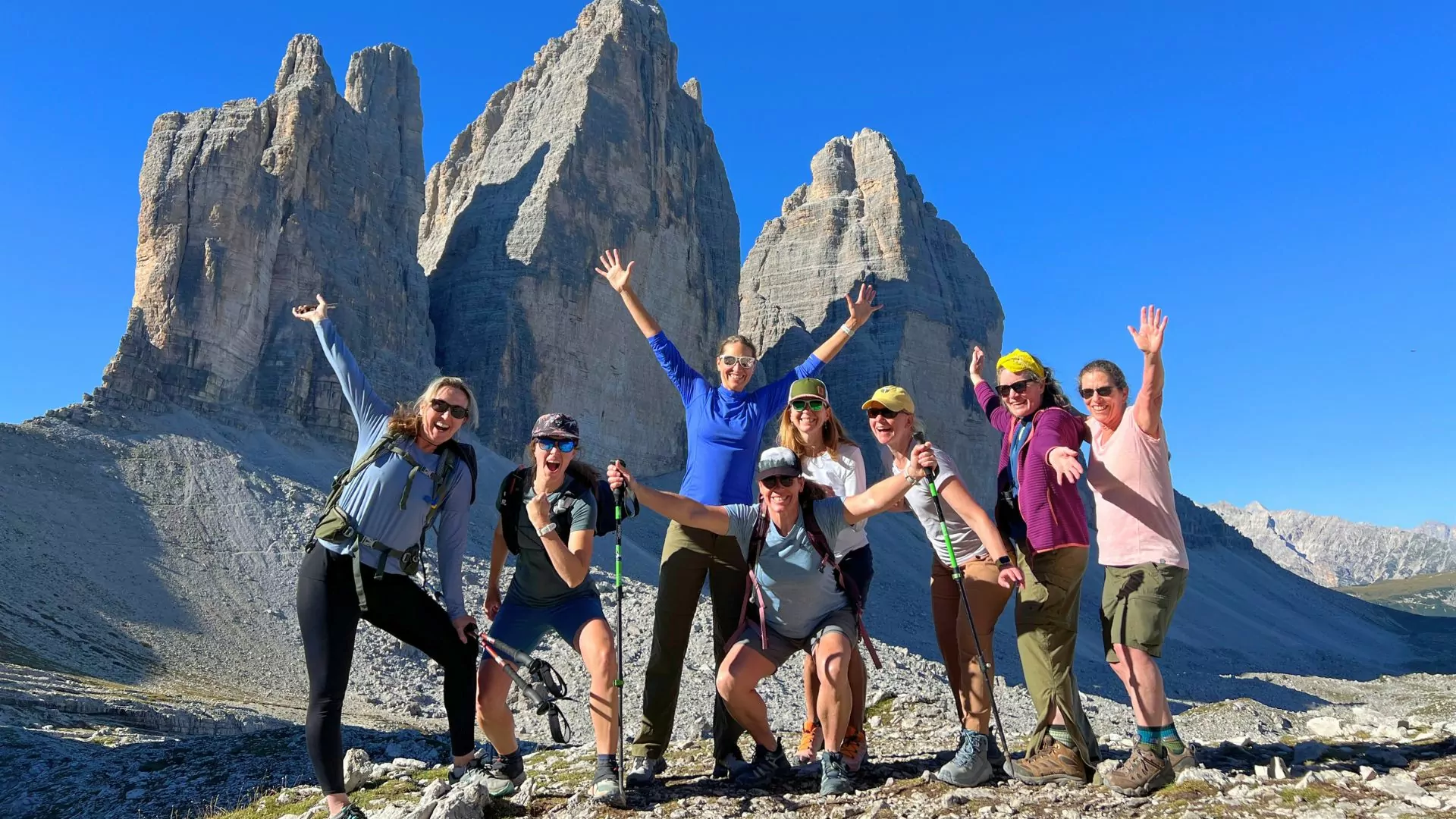 A group poses together in front of a rocky spire in the Dolomites