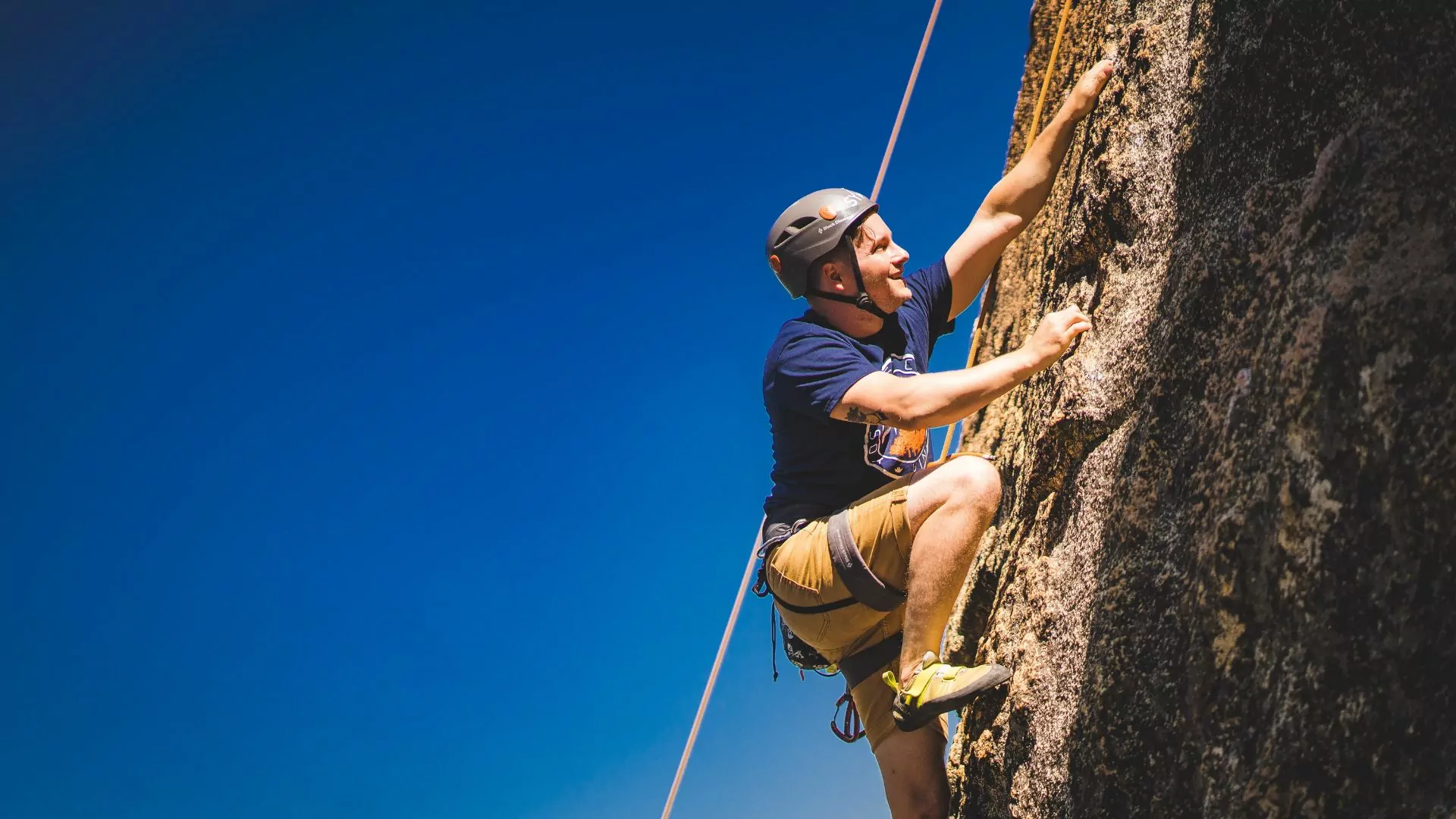A man climbs outdoors on top rope