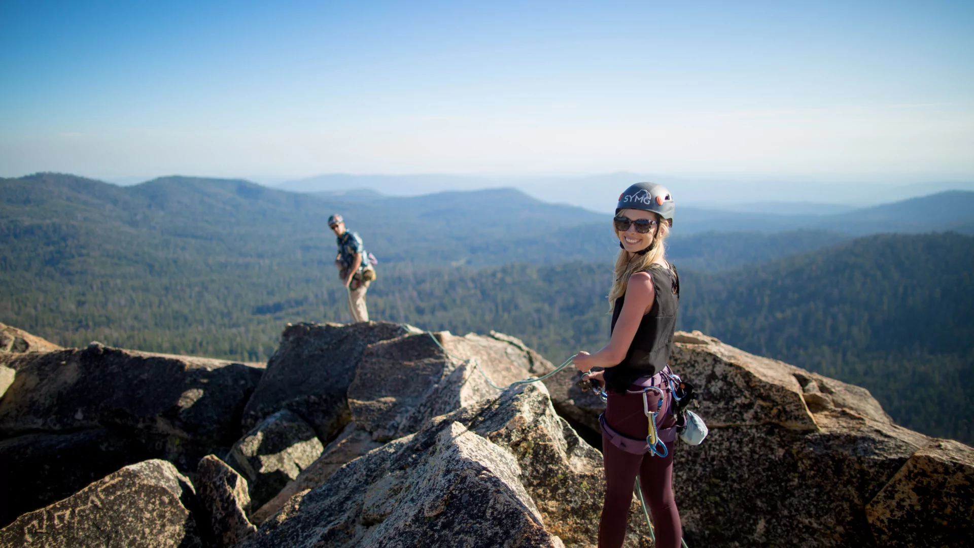 A woman looks at the camera high up on a rocky yosemite summit