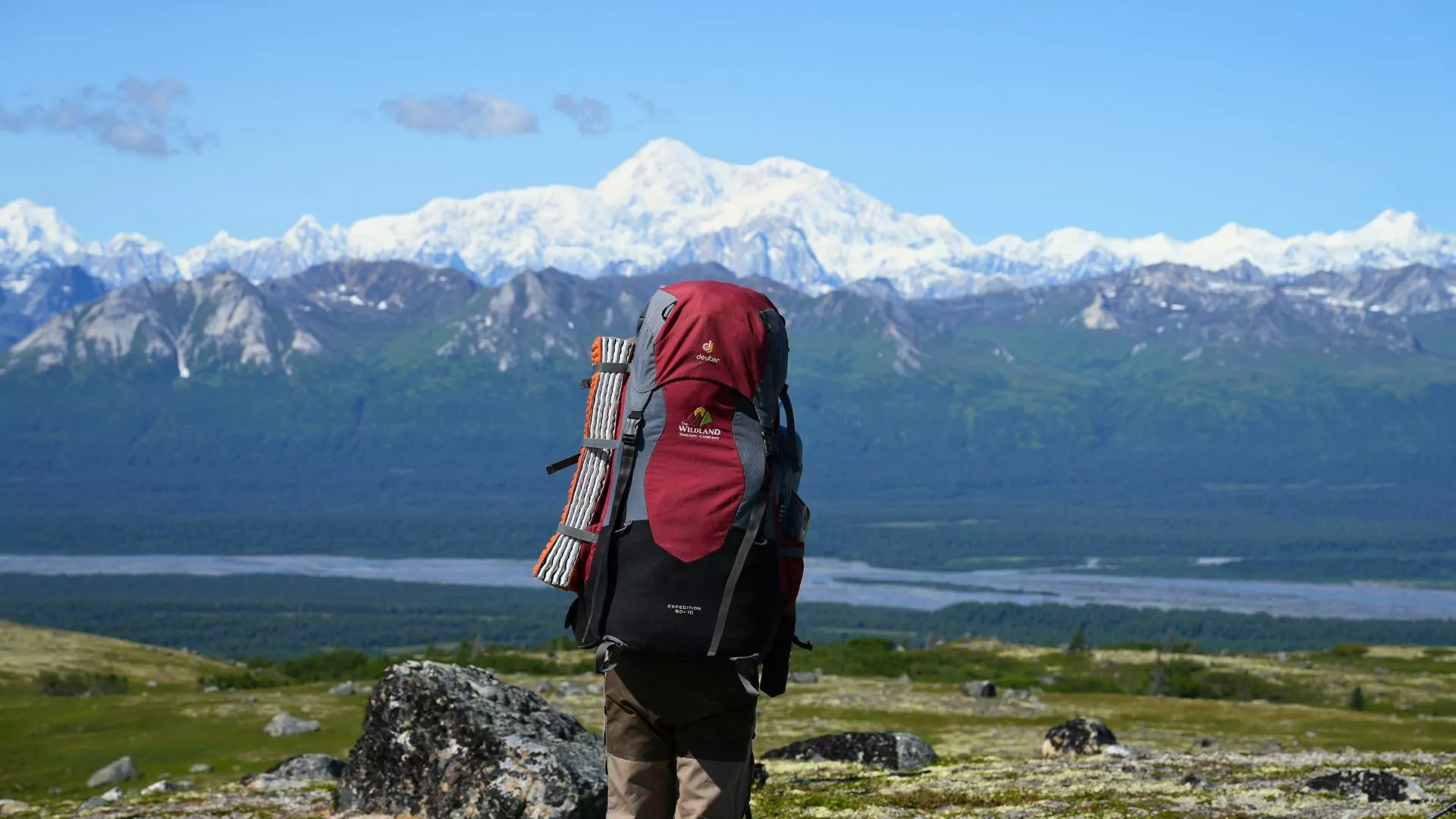 A hiker with a backpack on looks out into the distance