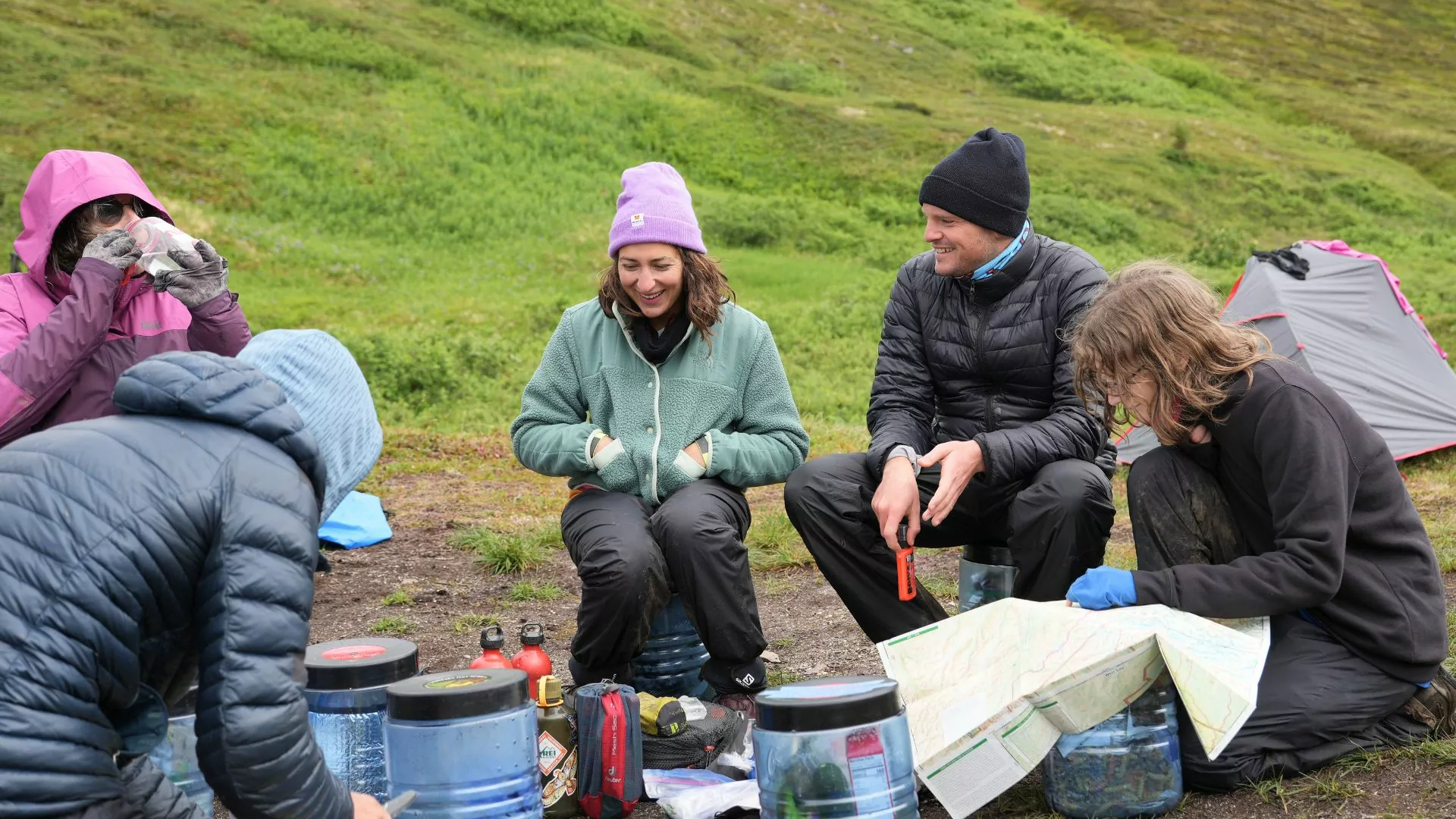 A group camping outdoors looks at a map