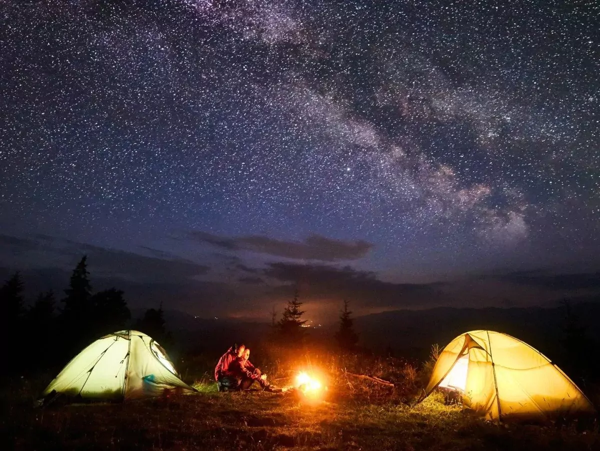 Tents at night|Meditation|Pills spill out of a bottle of melatonin|A tent in the woods under the night sky|A sleep mask|Looking out from inside a tent in a lsleeping bag|A woman does a yoga pose outdoors