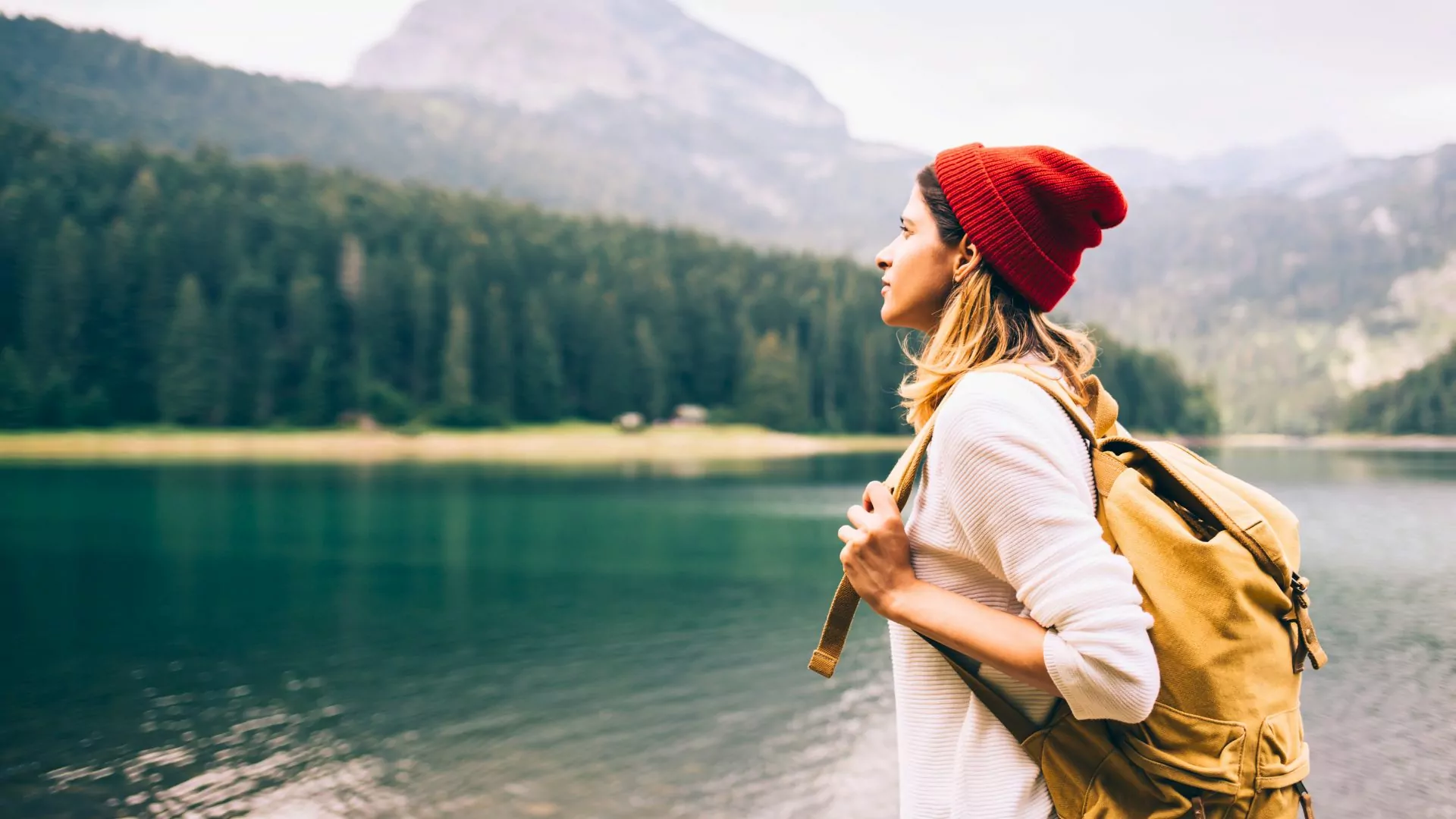 A woman with a daypack on stands outdoors