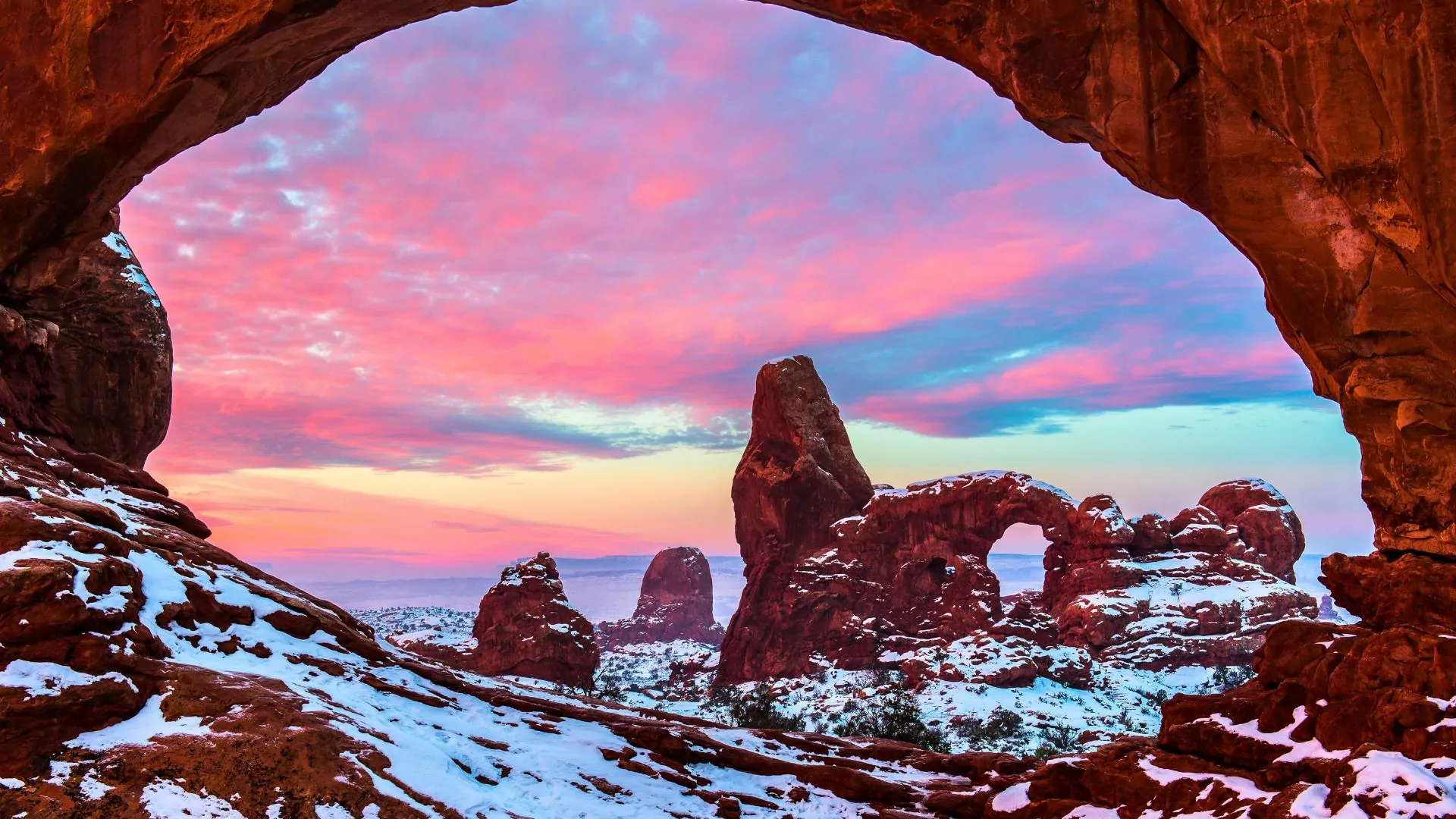 The sun rises on snow covered Arches in Moab