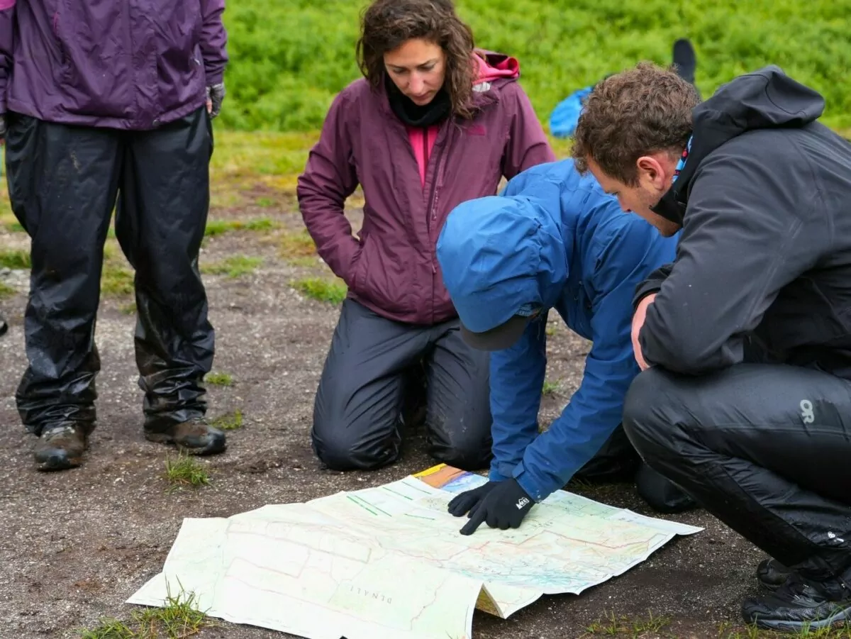 A group of people look at a map in the wilderness