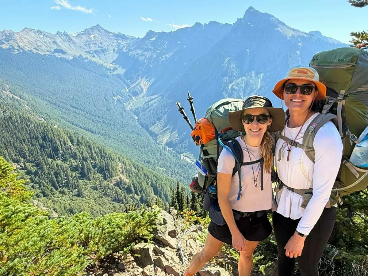 Two backpackers pose in front of Washington state summer scenery