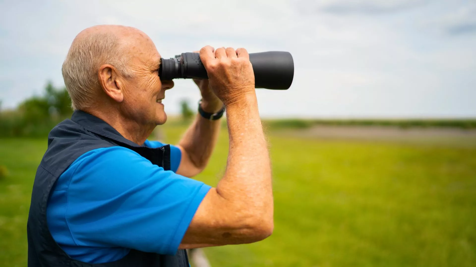 A man with binoculars looks into the distance